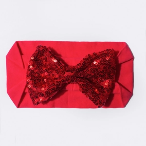 Détail à plat du bandeau bébé rouge élastique avec un grand nœud en paillettes