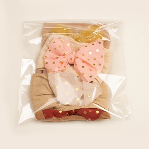 Detail of 4-pack baby headbands with polka dot bows in a transparent package