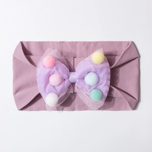 Detail of baby headband with purple mesh bow filled with colorful macaron pompoms