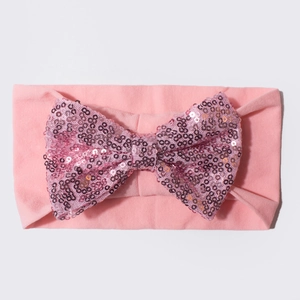 Bandeau élastique rose pour bébé avec un grand nœud en paillettes sur fond neutre