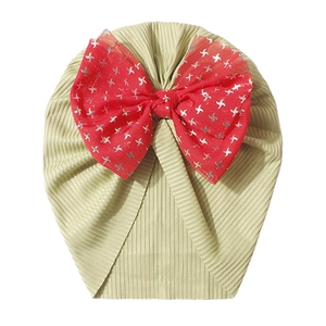 Detail of baby turban hat in sage green ribbed fabric with a large red mesh bow star print