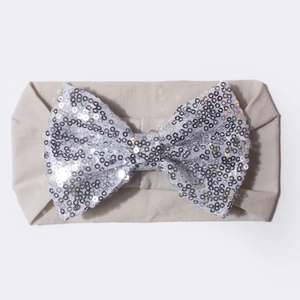 Détail du nœud à paillettes argentées sur un bandeau pour bébé en coton gris clair