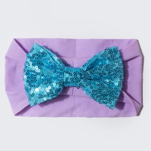 Détail d'un bandeau bébé avec nœud à paillettes bleues sur nylon violet élastique