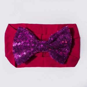 Détail du bandeau bébé avec un grand nœud pailleté sur un tissu en nylon doux