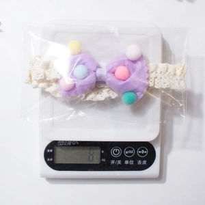 Weight measurement of purple lace flower baby headband showing 8g on a digital scale