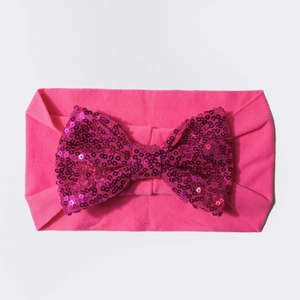 Détail du bandeau élastique pour bébé avec un grand nœud brillant orné de paillettes roses