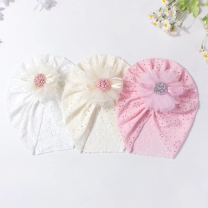 Close-up of baby lace hollow hats in white and pink with delicate layered mesh flowers