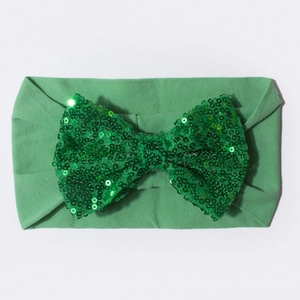 Gros plan d'un bandeau en nylon pour bébé avec un grand nœud en paillettes vertes