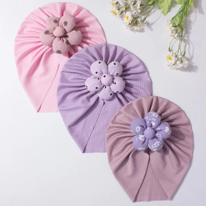 Three-piece baby turban hats with large fabric flowers on white background close-up