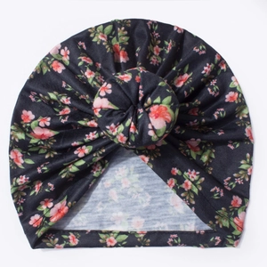 Détail du bonnet donut bébé noir à fleurs roses avec un nœud en coton extensible