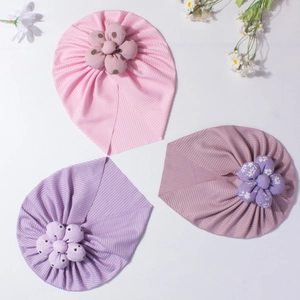 Detailed view of three baby flower turbans in pink, purple, and mauve soft ribbed fabric