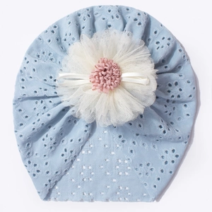 Close-up of baby turban cap with blue eyelet embroidery and a 3D floral bow detail