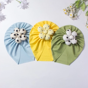 Three colorful baby turbans with decorative fabric flowers and heart-dot patterns