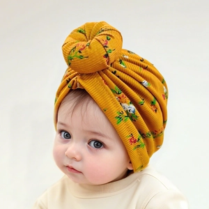 Detail of baby donut turban hat in ginger yellow with floral print and ribbed fabric