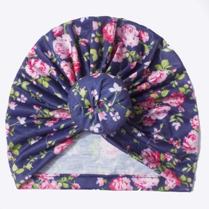 Détail du turban pour bébé avec imprimé floral rose sur tissu bleu foncé doux