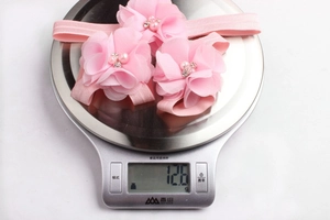 Detailed view of handmade chiffon floral headbands with pearls on an electronic scale