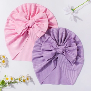 Close-up of pink and lavender baby turban hats featuring large bows and ribbed knit fabric