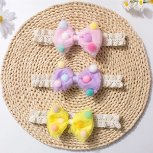 Three-piece set of baby lace headbands with pastel pompoms on woven mat detail
