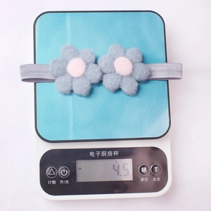 Gros plan détaillé d'un bandeau à fleurs en feutre bleu clair pesant 4,5 g sur une balance