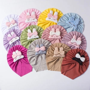 Flat lay of colorful baby bunny hats with cute ribbon bows in twelve bright vibrant shades
