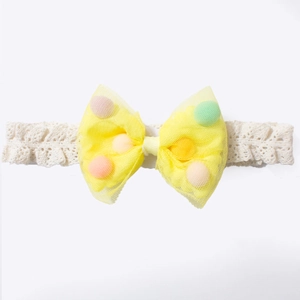 Detailed view of yellow mesh bow baby headband with colorful pom-poms and white lace