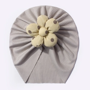 Detailed view of light grey ribbed baby turban hat with a yellow polka dot flower ornament