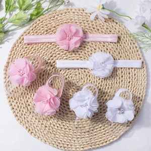 Pink and white chiffon baby headband and foot flower set with pearls on woven mat