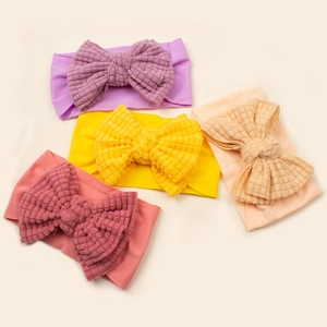 Set of four soft waffle fabric baby bow headbands in purple, yellow, pink, and orange