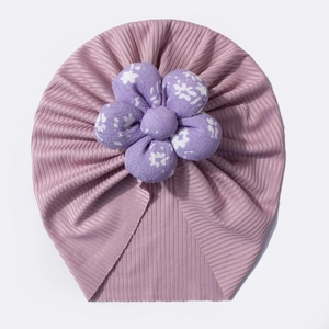 Detail of light purple ribbed knit baby turban hat with a large 3D floral decoration