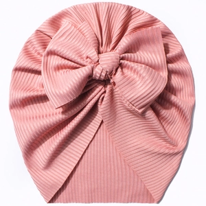 Detail view of pink ribbed knit baby turban hat featuring a large handmade bow decoration