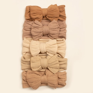 Détail de cinq bandeaux pour bébé aux tons terre avec texture en maille torsadée élastique