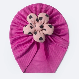Close-up of baby beanie with pink heart pattern flower and ribbed fabric texture