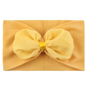 Détail du bandeau bébé en nylon souple jaune vif orné d'un grand nœud papillon en mousseline