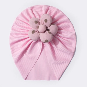 Detail of pink ribbed knit baby turban hat featuring a large brown polka dot fabric flower