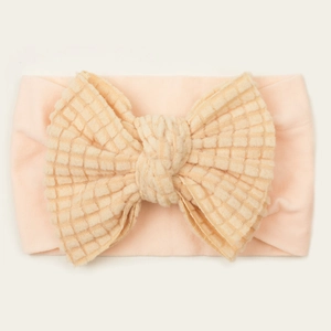 Close-up of baby headband with waffle texture bow in soft skin pink color