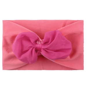 Détail d'un bandeau rose souple en nylon pour bébé avec un grand nœud en mousseline