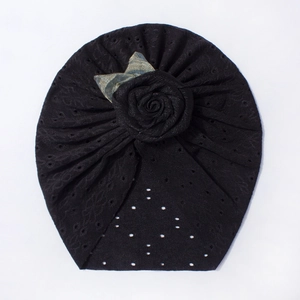 Dettaglio del turbante nero per neonati in maglia traforata con rosa 3D e fiocco in denim