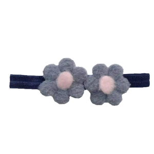 Détail d'un bandeau bébé élastique bleu marine avec deux fleurs en peluche bleu-gris