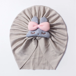 Detailed view of grey ribbed baby turban with plush bunny ears and pink bow detail