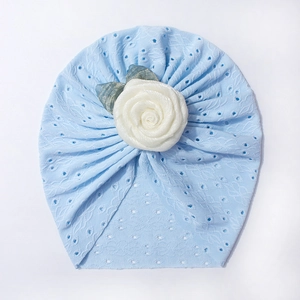 Dettaglio del turbante in pizzo azzurro traspirante con grande rosa bianca 3D per neonati