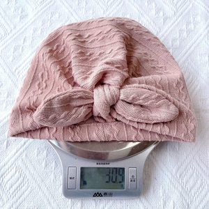 Detail showing pink infant turban hat weighing only 30.9g on a digital scale for comfort