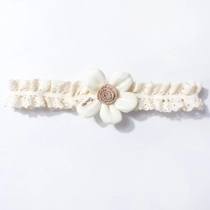 Detail of cream lace baby headband with large silk flower and fine embroidery