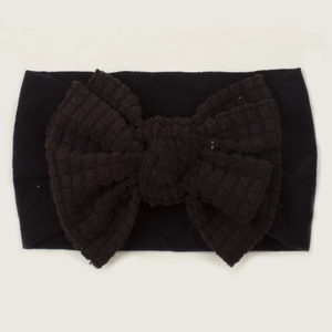 Detail view of baby headband featuring a black waffle knit oversized bow decoration