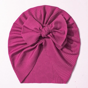 Close-up of bright rose pink rib-knit baby turban hat with a large decorative bow detail
