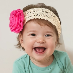 Détail du bandeau bébé avec fleur en tissu rouge rose et large dentelle beige souple