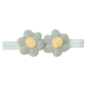Détail de fleurs en peluche vert menthe sur un bandeau élastique pour bébé