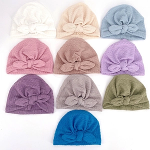 Flat lay of soft ribbed knit baby beanies featuring decorative large bow knots in ten colors