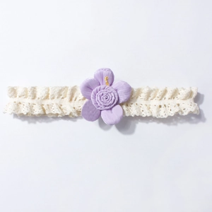 Detail of baby lace headband featuring a soft lilac fabric flower with yellow center