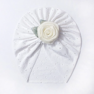 Dettaglio del turbante bianco traspirante per neonati con grande decorazione floreale