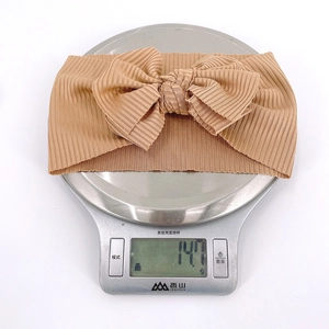 Bandeau bébé léger avec grand nœud rayé pesant 14,7g sur une balance de cuisine